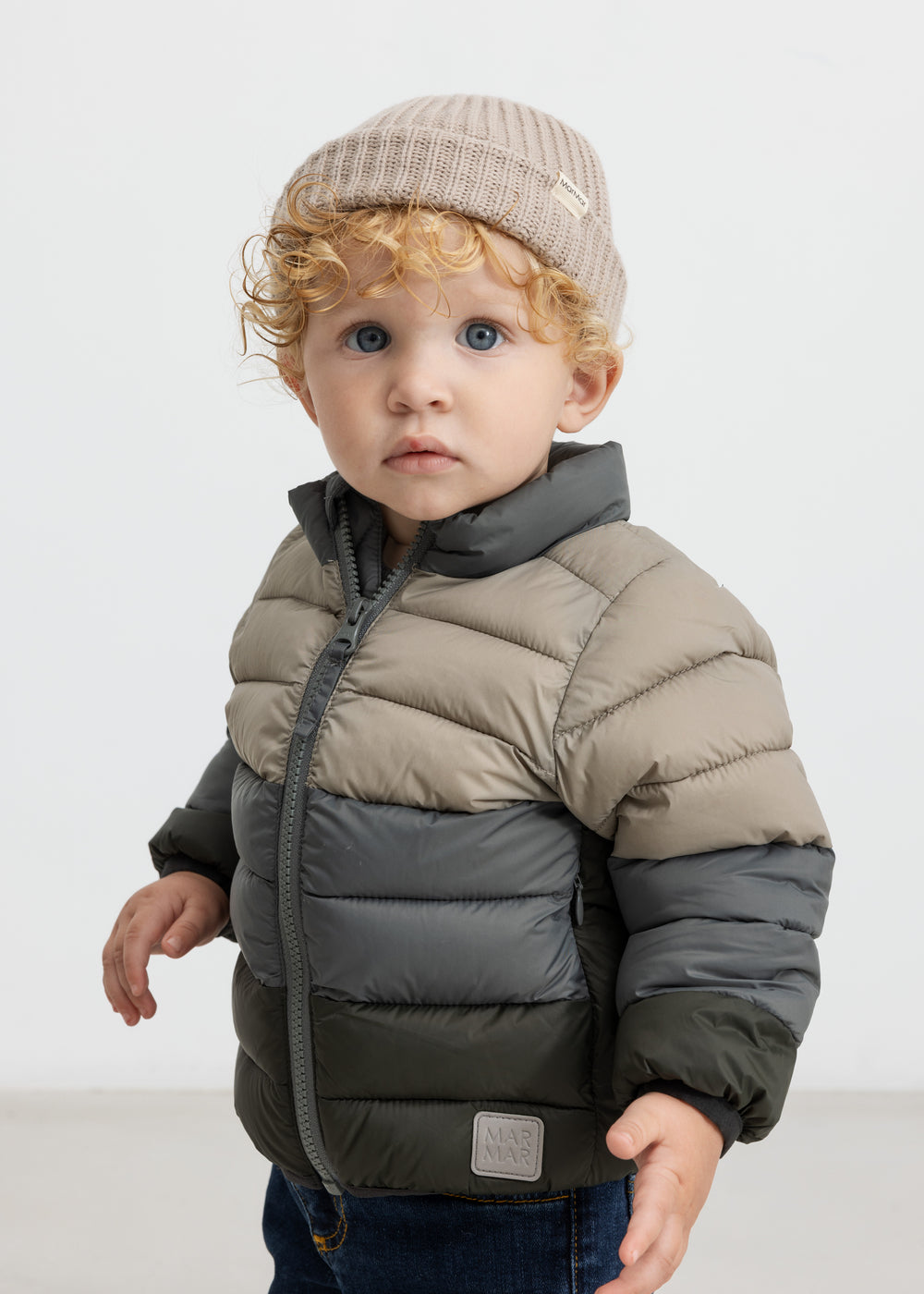 Barn iført beige strikhue og todelt dunjakke
