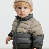 Barn iført beige strikhue og todelt dunjakke