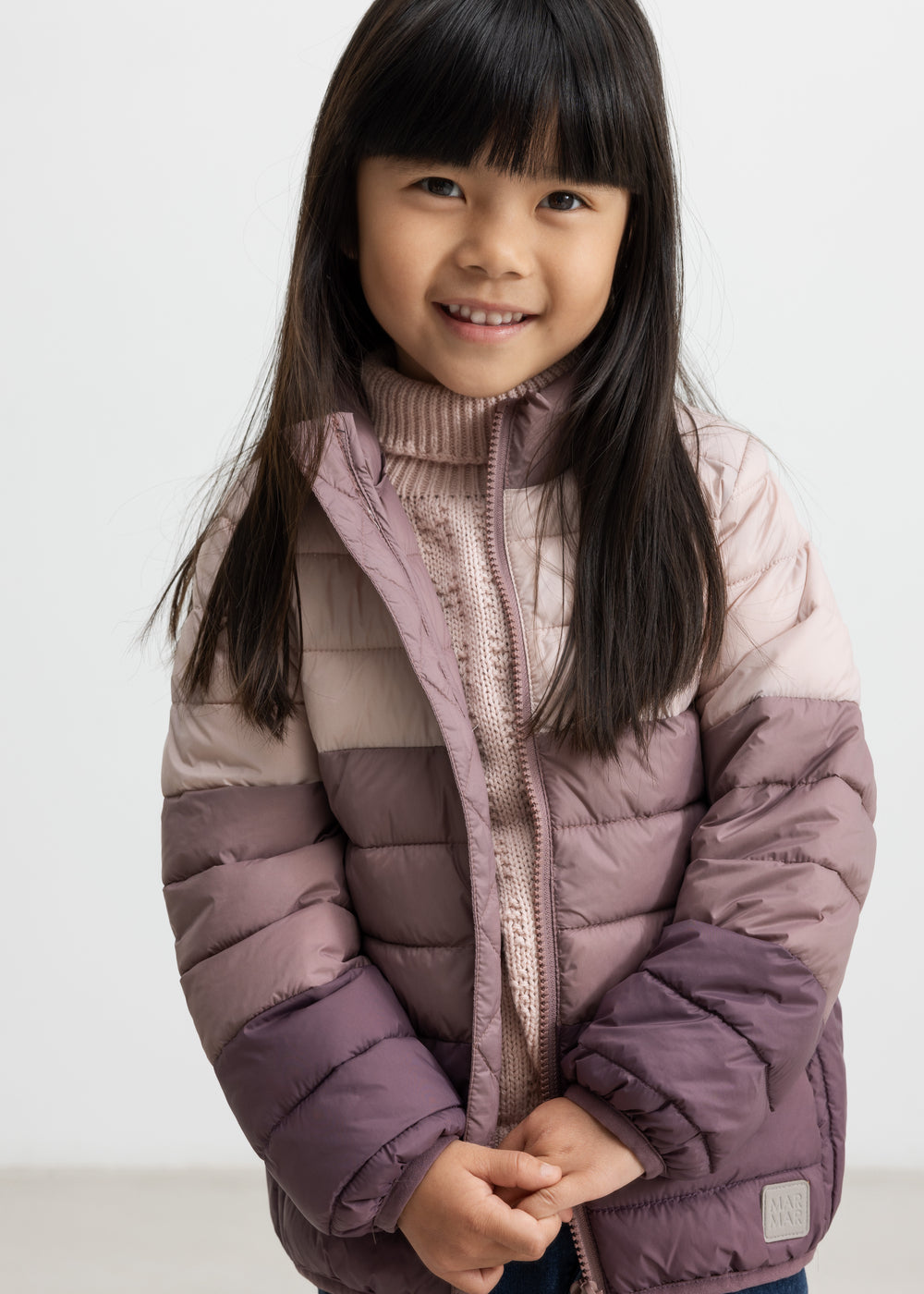 Pige iført vatteret jakke i rosa og lilla nuancer