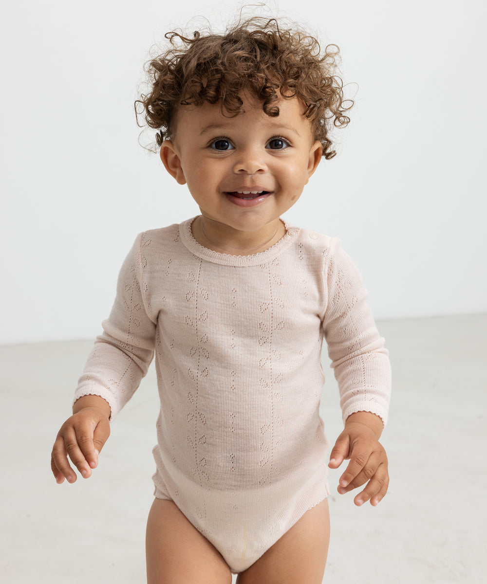 Baby iført lyserød body i merinould