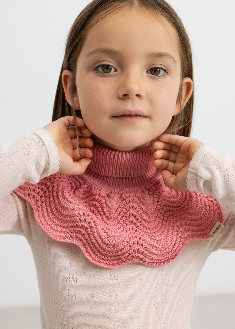 Pige med lyserød bluse i merinould og mørkrosa halsedisse