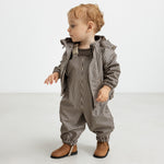 Baby i regnsæt med brune striber og hætte, står op