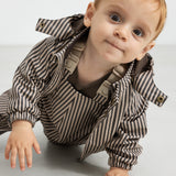 Baby i regnbukser med brune striber og jakke, kravler fremad