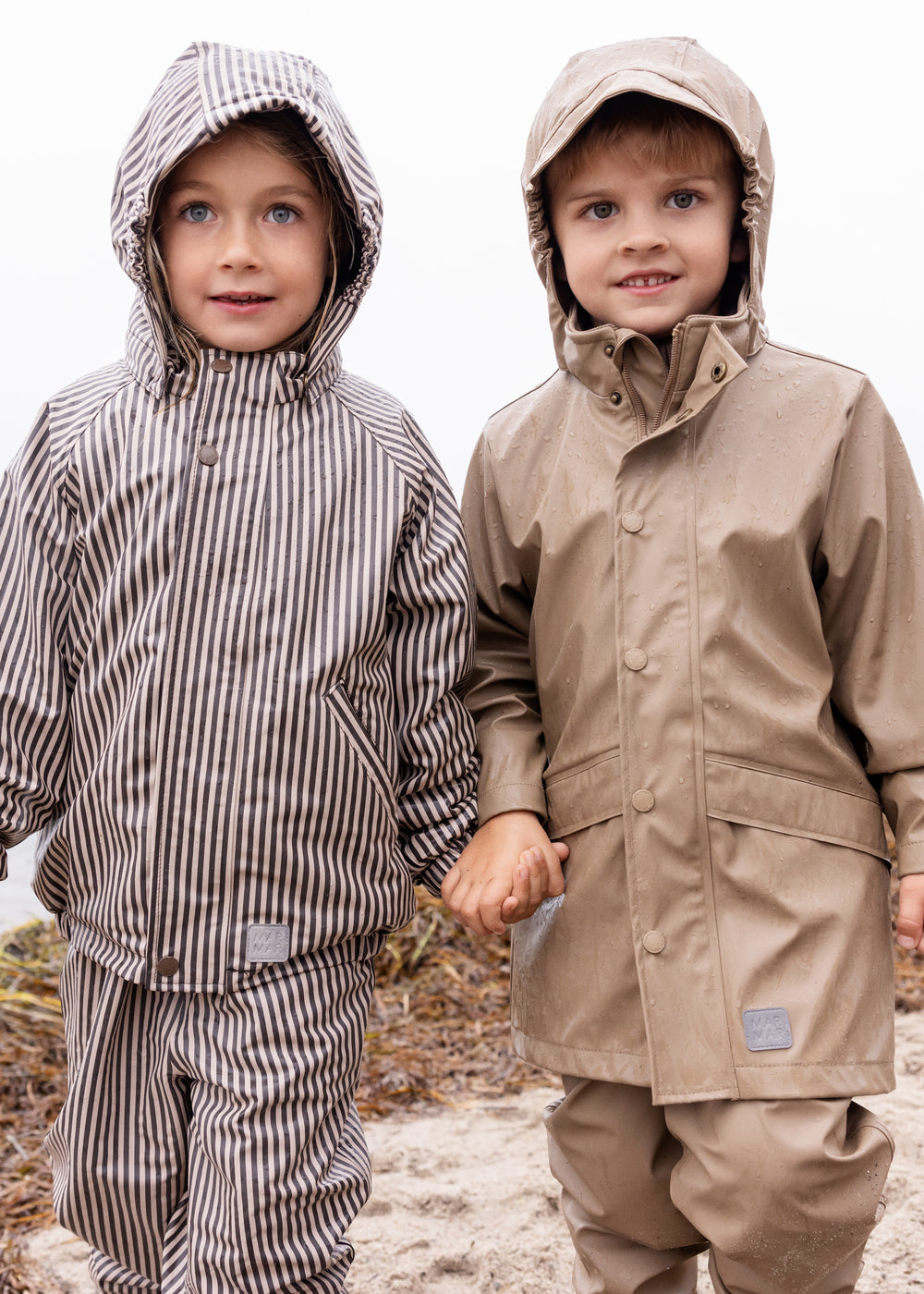 to børn i regntøj, venstre barn iført brunt stribet sæt med hætte