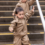 Tre børn på trappe, to iført beige regnsæt 