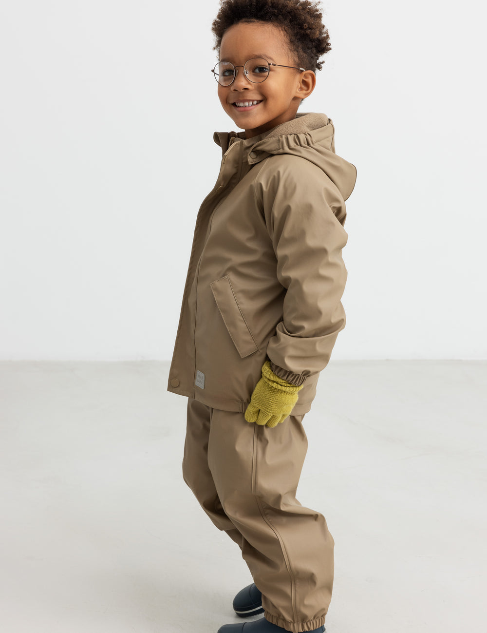 Børn iført beige regnjakke og bukser