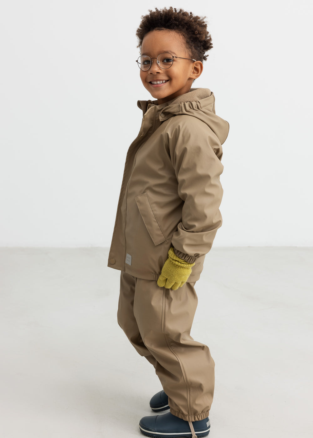 Børn iført beige regnjakke og bukser