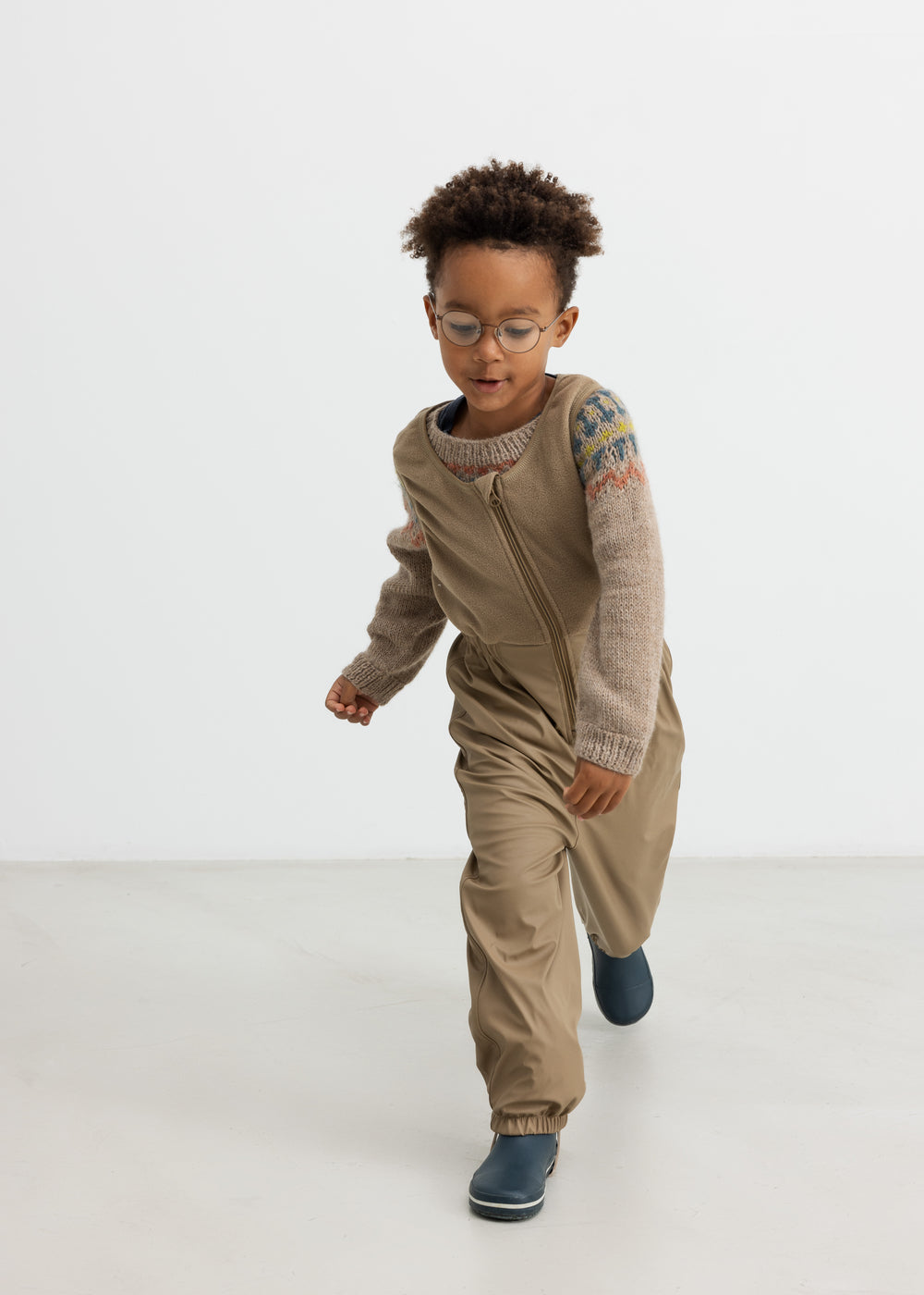 Dreng iført beige uldstrikbluse med mønster leger