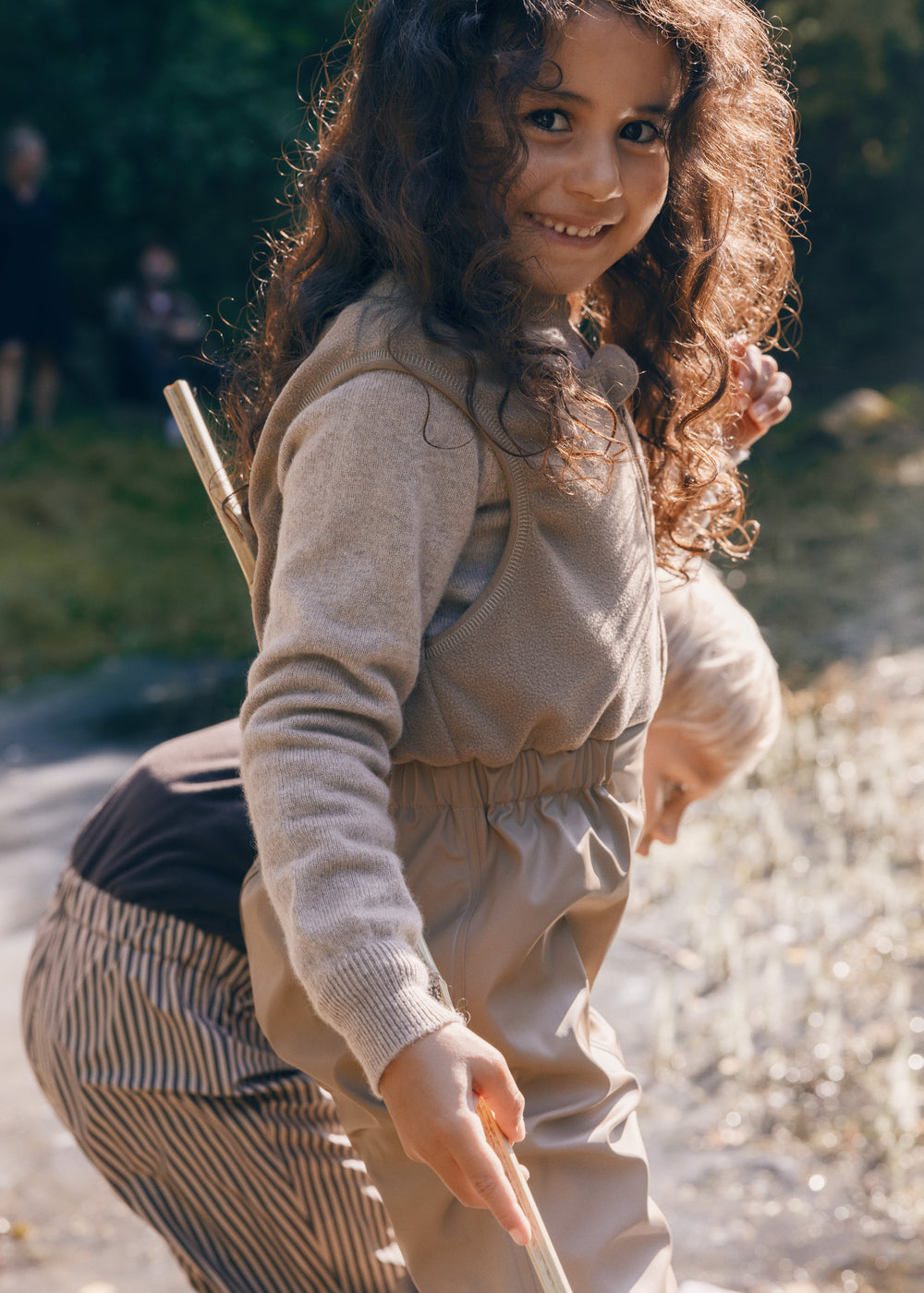 Pige iført beige selebukser og lys trøje i naturen