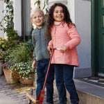 Pige i lyserød termojakke står med scooter ved siden af en dreng