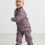 Barn iført støvlilla termotøj med print, smilende og i bevægelse