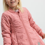 Barn iført lyserød termojakke, smilende og med hånden i lommen