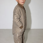 Dreng iført brunternet termojakke og hue, står i profil