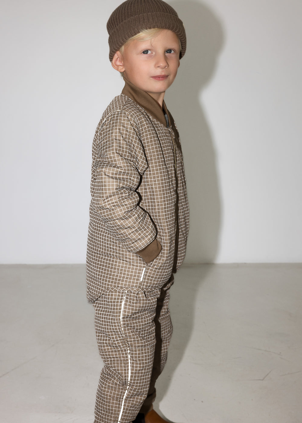 Barn i brunternet termotøj med hætte, hænderne i lommerne