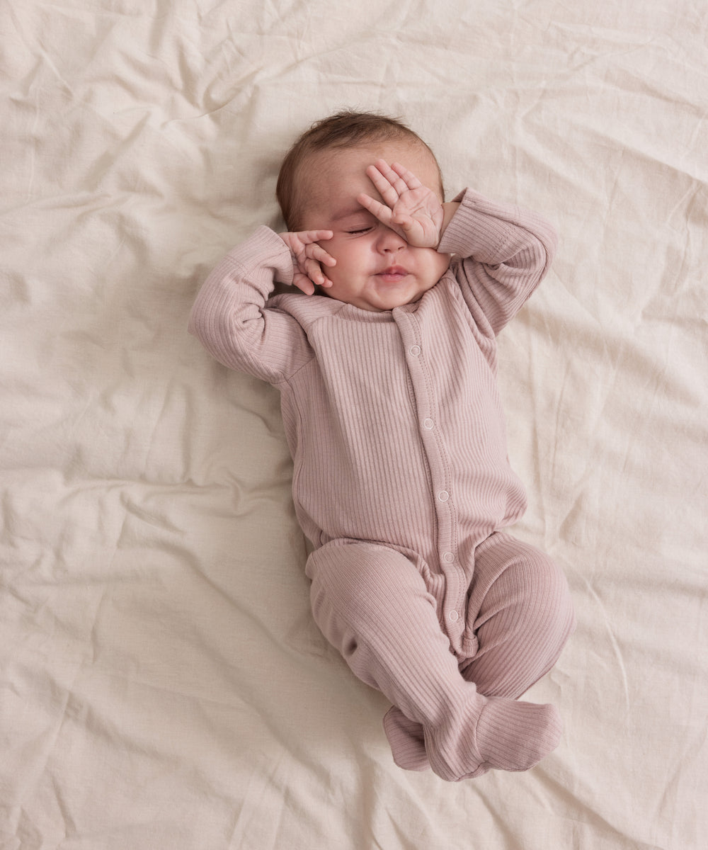 Baby i ribbstrikket lyserød heldragt til baby i blødt materiale med lange ærmer, lange ben, tryknapper og futter