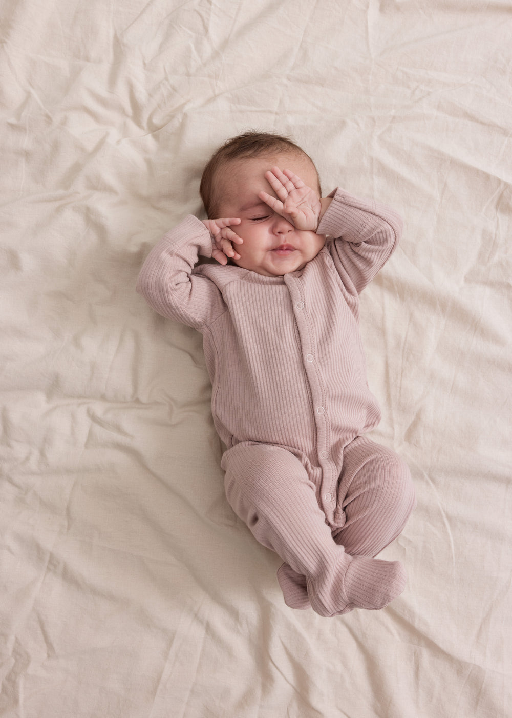 Baby i ribbstrikket lyserød heldragt til baby i blødt materiale med lange ærmer, lange ben, tryknapper og futter