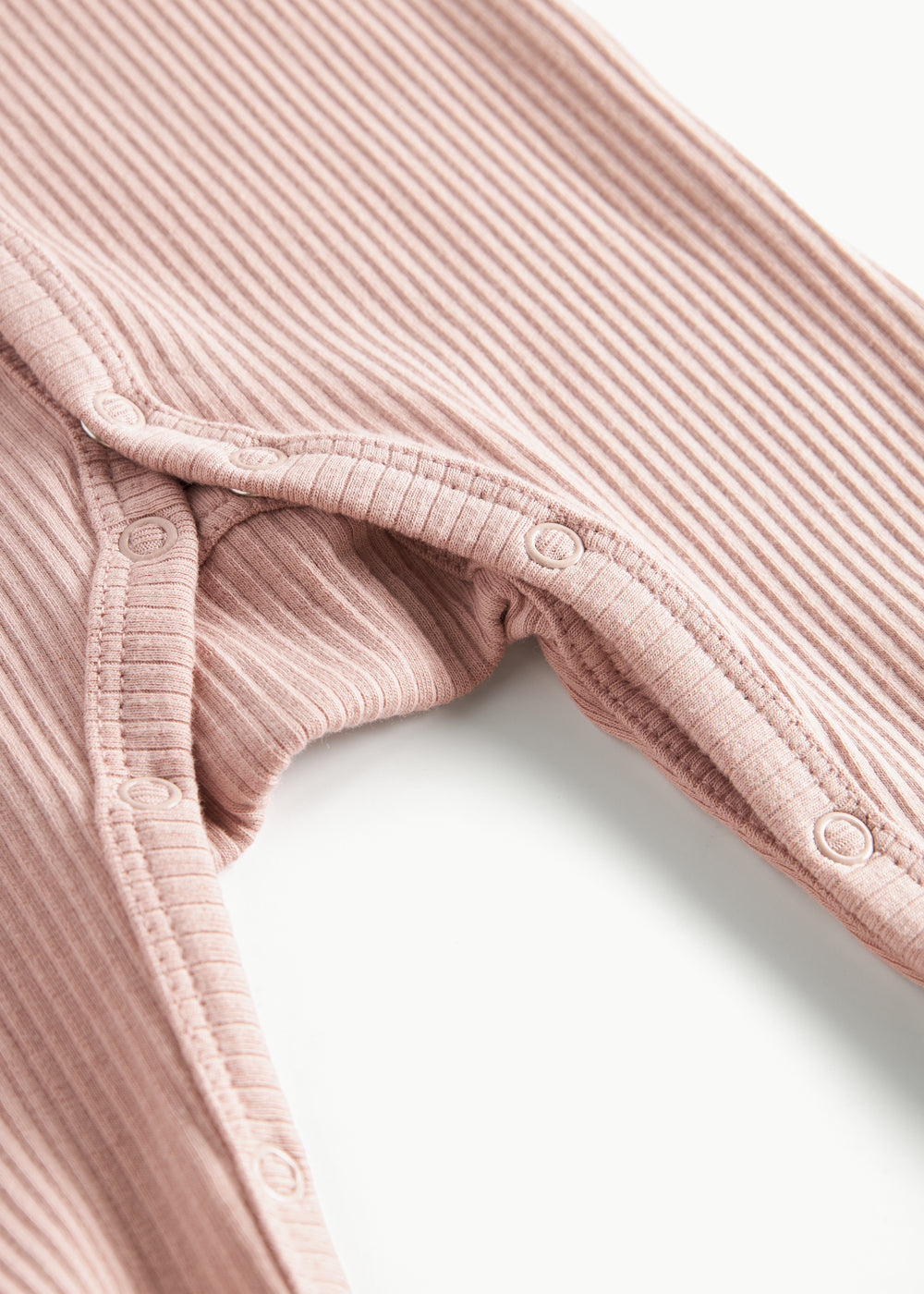 ribbstrikket lyserød heldragt til baby i blødt materiale med lange ærmer, lange ben, tryknapper og futter