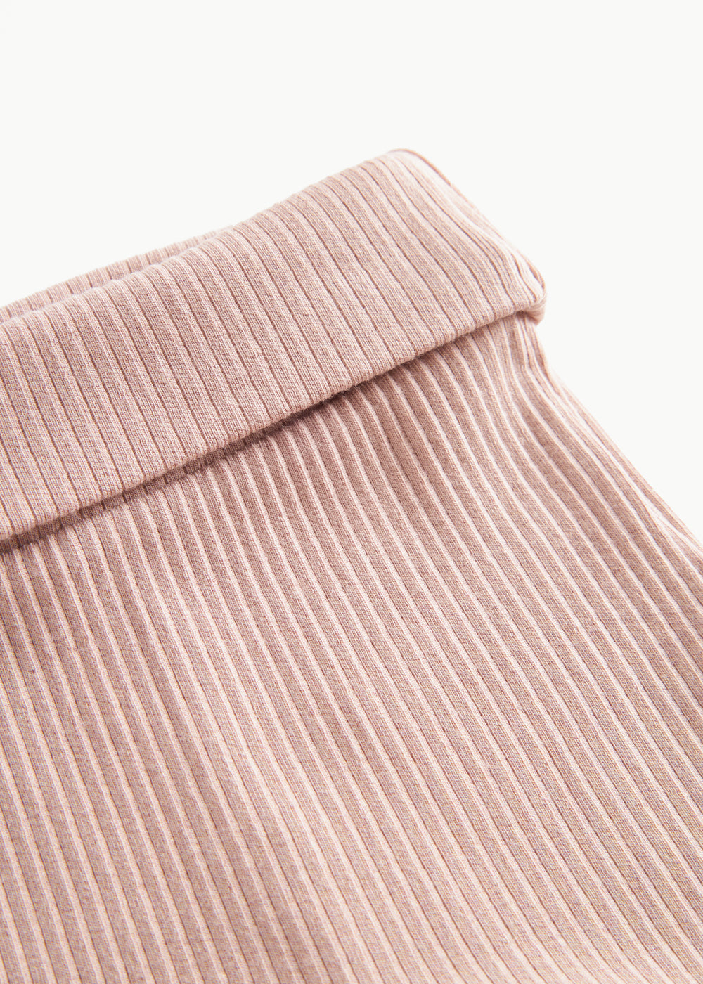 Nærbillede af ribstrikket elastisk talje på lyserøde leggings med fod til baby