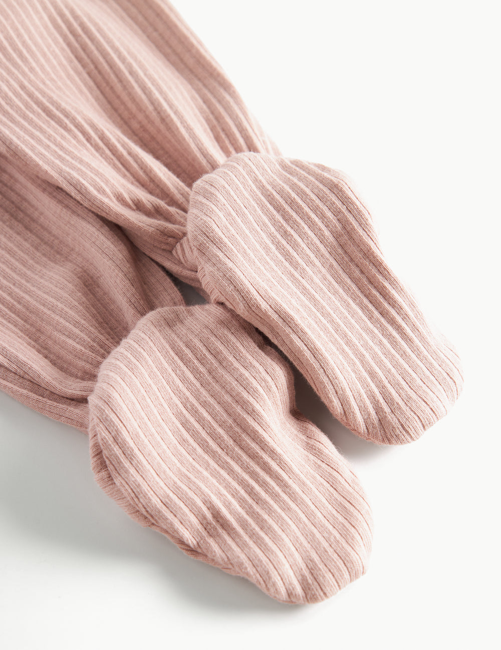 Detaljebillede af fod på lyserøde ribstrikkede bukser til baby