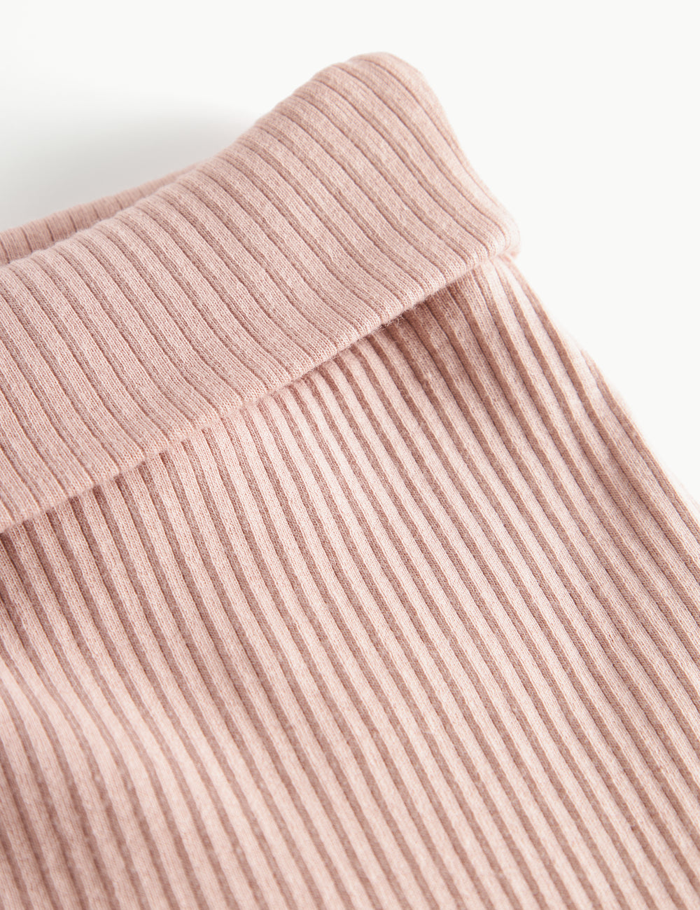 Nærbillede af ribstrikket stof og elastik i taljen på lyserøde babybukser