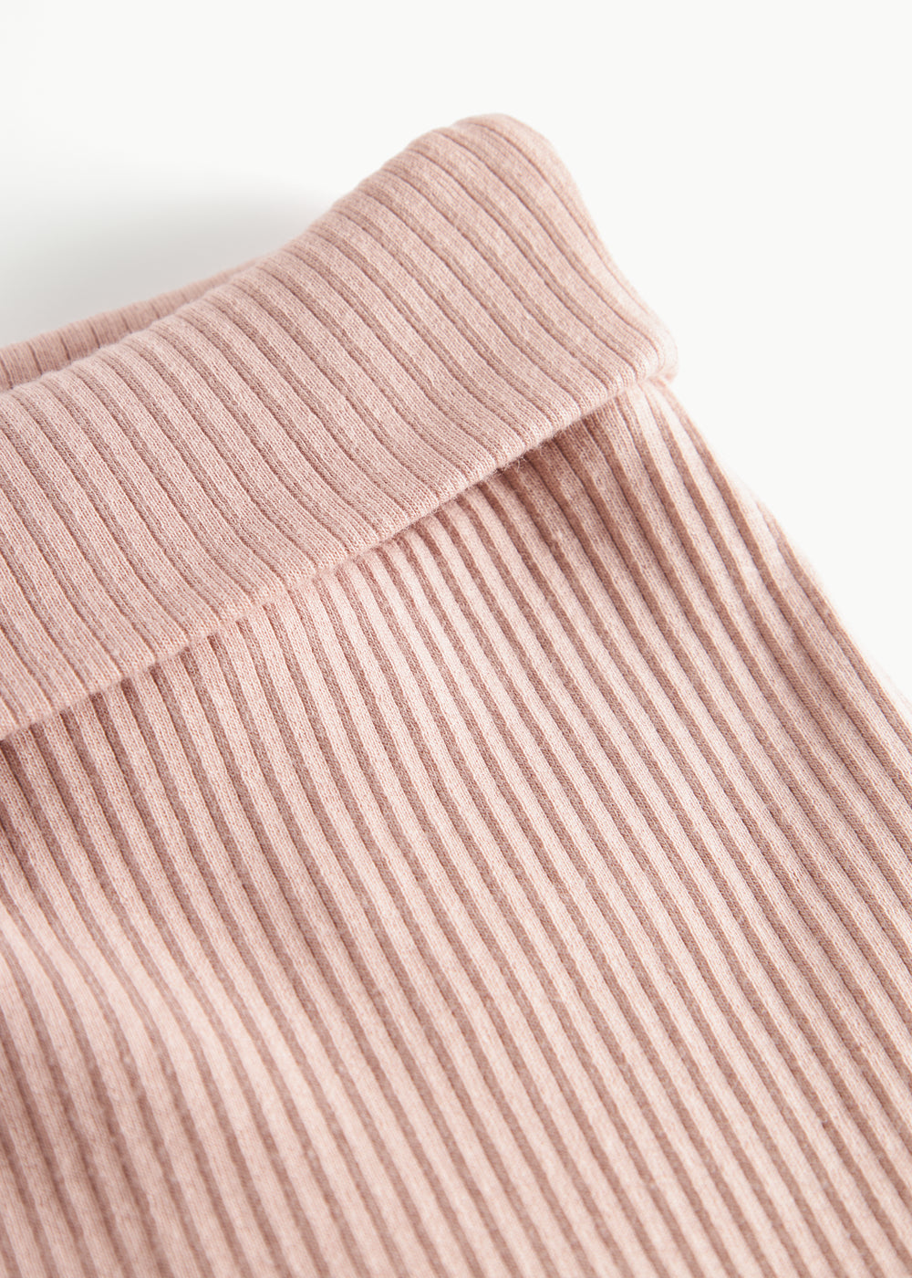 Nærbillede af ribstrikket stof og elastik i taljen på lyserøde babybukser