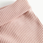 Nærbillede af ribstrikket stof og elastik i taljen på lyserøde babybukser