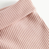 Nærbillede af ribstrikket stof og elastik i taljen på lyserøde babybukser