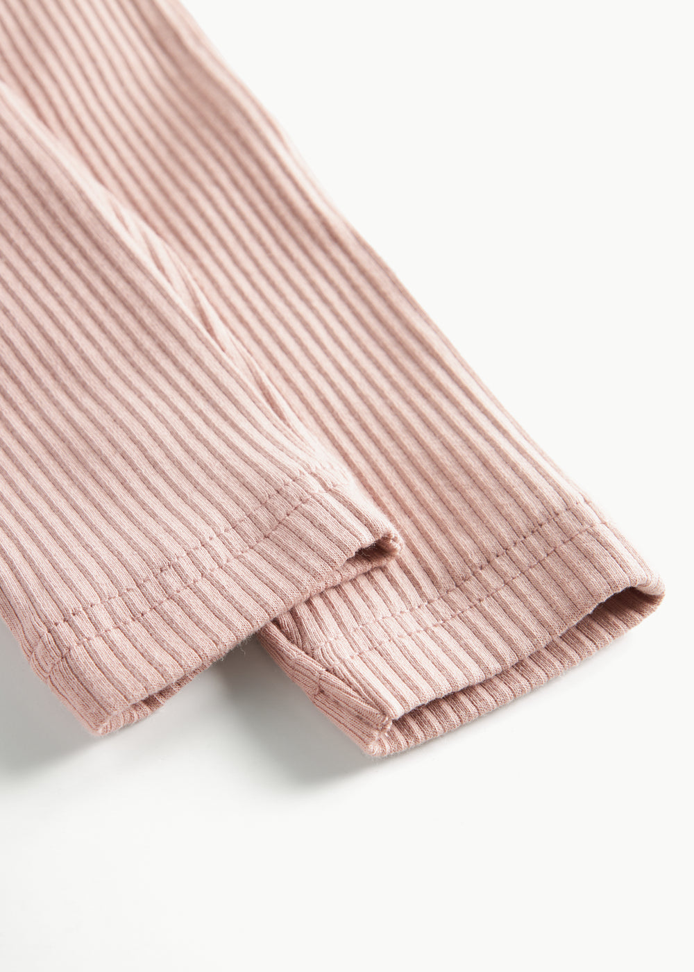 Detaljebillede af benåbning på lyserøde ribstrikkede bukser til børn