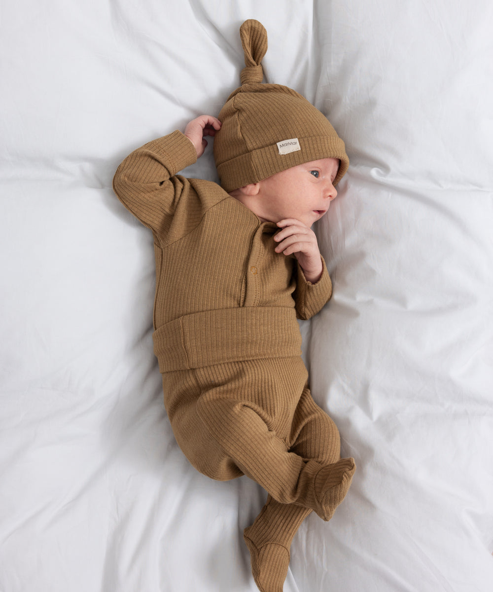 Baby iført brun ribstrikket babybody med knapper foran og babyhue