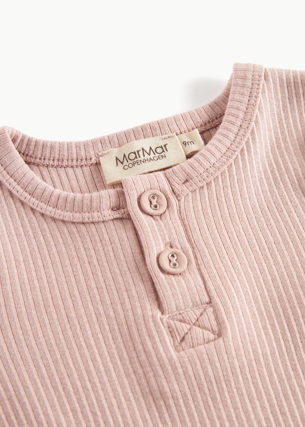 Lyserød ribstrikket babybody med lange ærmer, stolpe knaplukning og trykknapper mellem benene