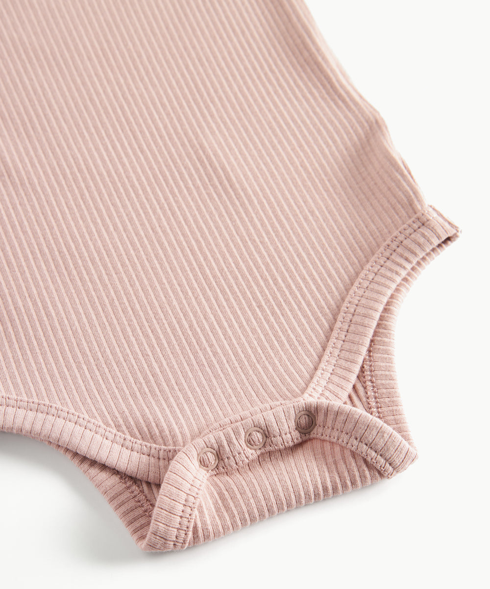 Lyserød ribstrikket babybody med lange ærmer, stolpe knaplukning og trykknapper mellem benene