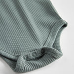 Grøn ribstrikket body med lange ærmer og knapper til baby