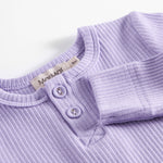 Lilla ribstrikket babybody med lange ærmer, stolpe knaplukning og trykknapper mellem benene