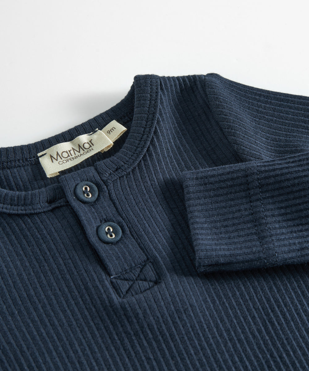 Blå ribstrikket babybody med lange ærmer, stolpe knaplukning og trykknapper mellem benene