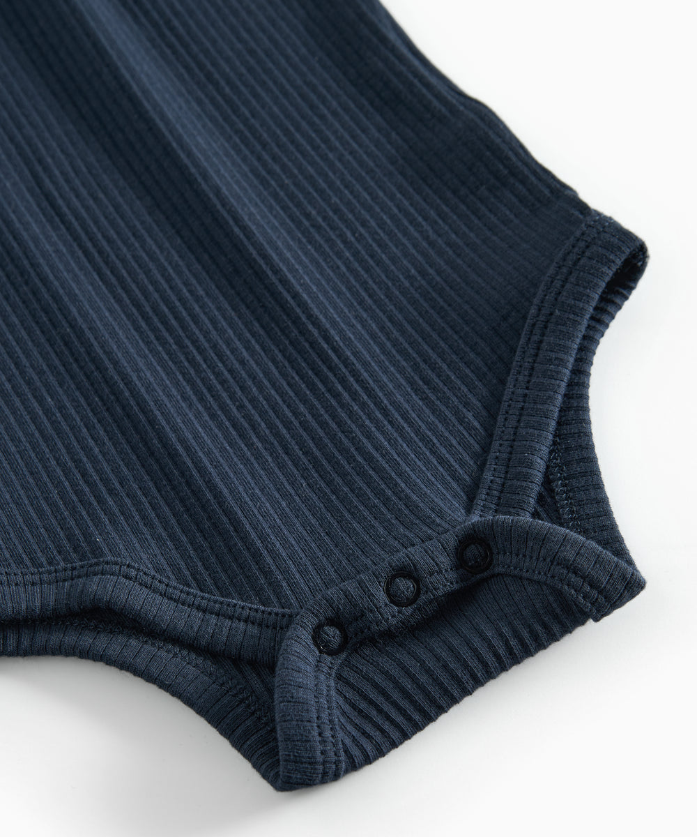 Blå ribstrikket babybody med lange ærmer, stolpe knaplukning og trykknapper mellem benene