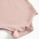 Detaljebillede af trykknapper ved benåbning på lyserød body til baby