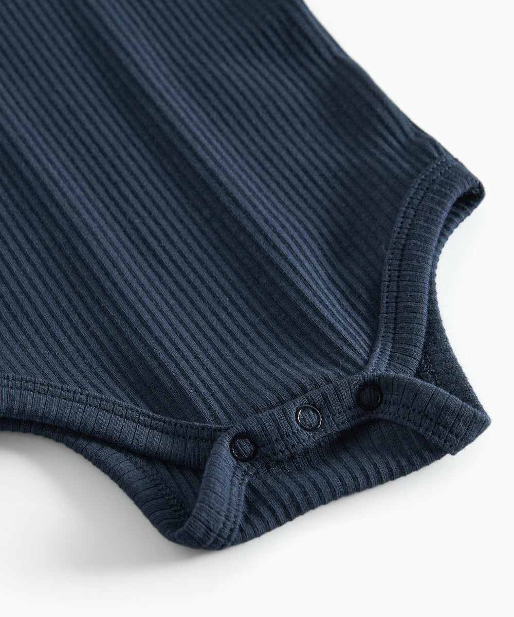 Blå ribstrikket babybody med lange ærmer og knapper mellem benene