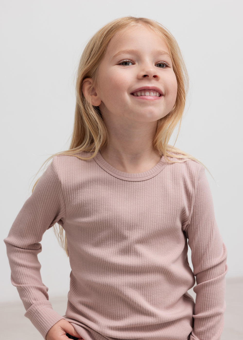 Glad pige iført langærmet rosa ribstrikket t-shirt til børn