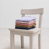 Stak af børne t-shirts i flere farver placeret på stol