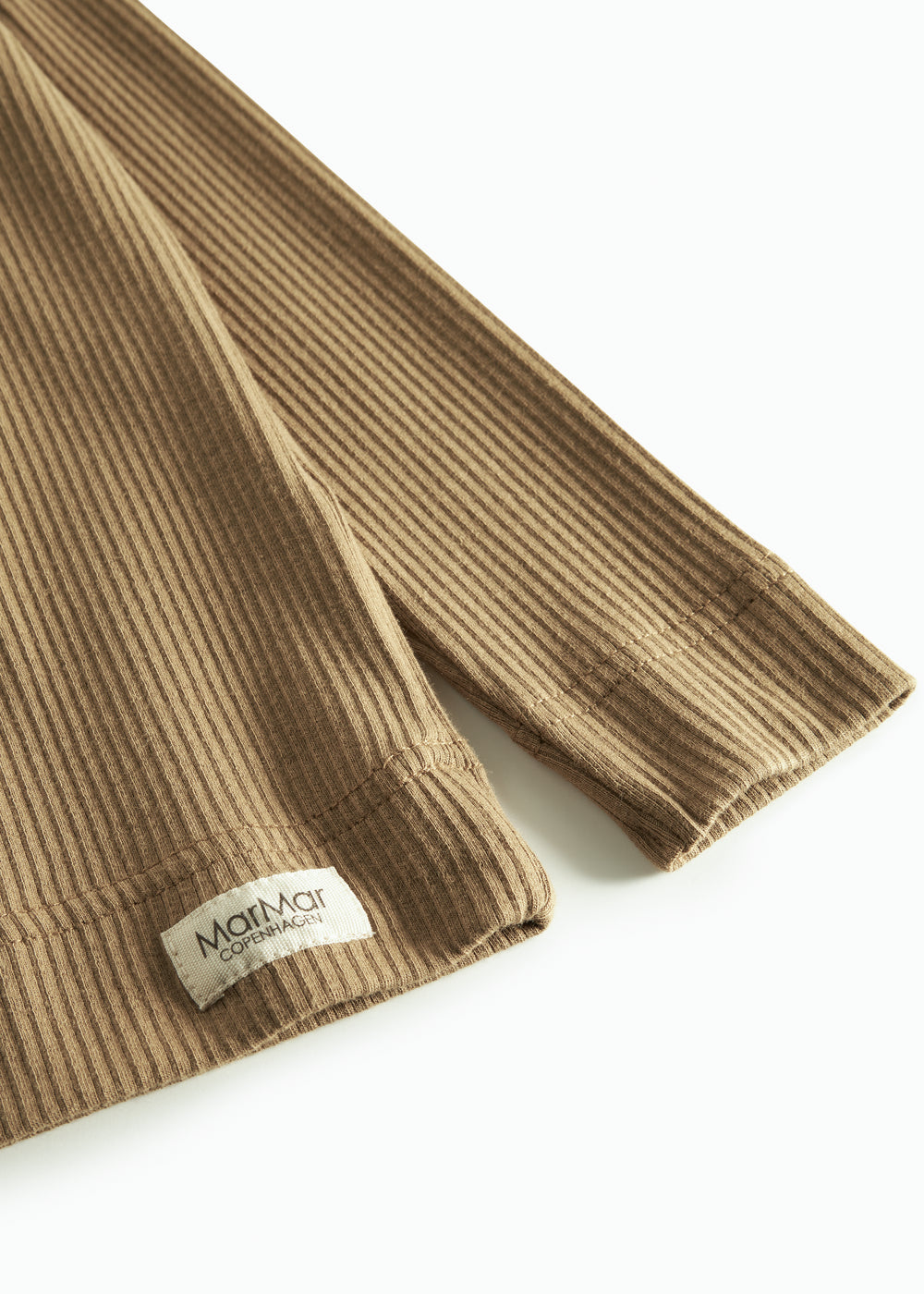 Nærbillede af ribstrikket stof og mærkat på brun børnetrøje