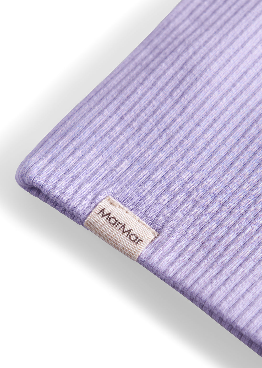 Detalje af ribstrikket lyse lilla stof og mærke på børnehue