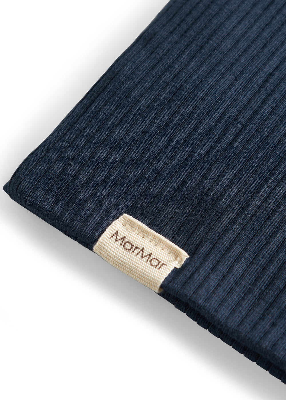 Detalje af ribstrikket navy blå stof og mærke på børnehue