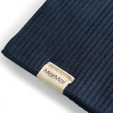 Detalje af ribstrikket navy blå stof og mærke på børnehue