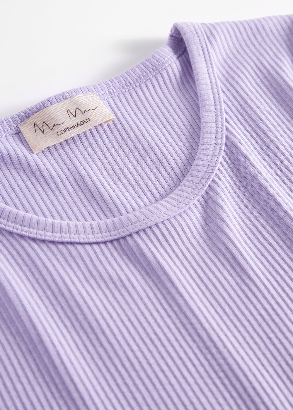 Detalje af ribstrikket stof ved halsudskæringen på lys lilla dame t-shirt