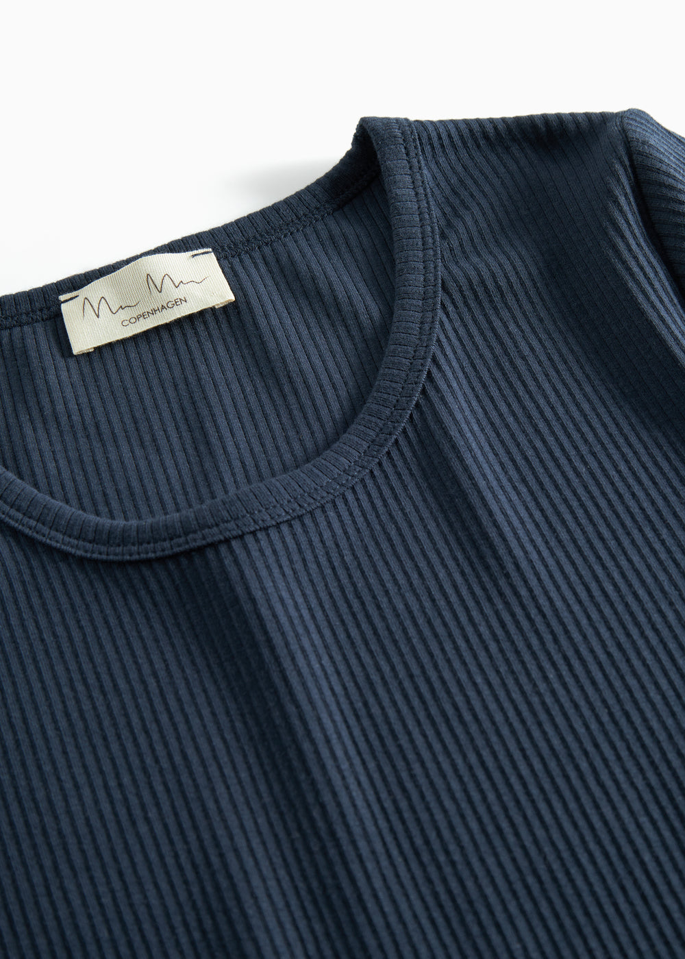 Detalje af ribstrikket stof ved halsudskæringen på mørkeblå t-shirt til dame