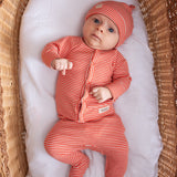 Baby iført koralfarvet stribet sæt med hue, cardigan og bukser i en fletkurv