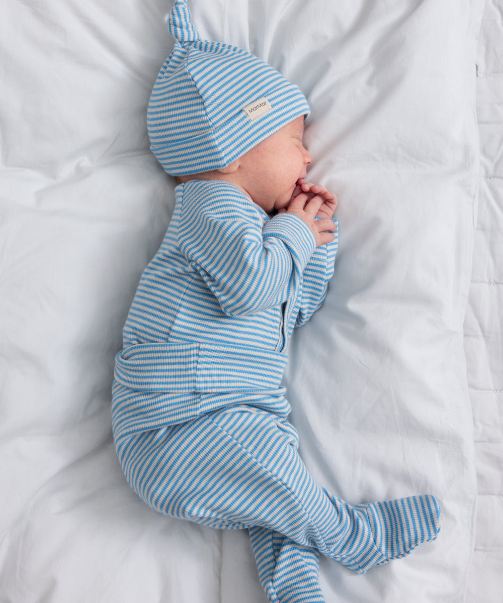 Baby iført blå og hvid stribede bukser og matchende hue sover