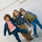 Tre børn iført efterårstøj med strik og denimjakker og tørklæde