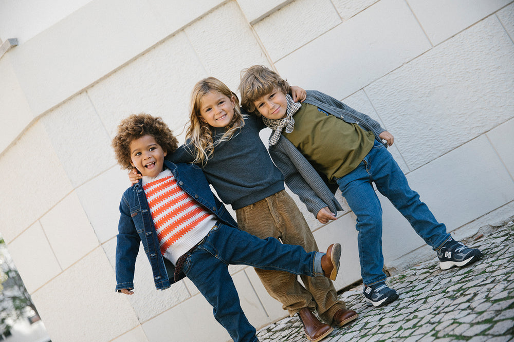 Tre børn iført efterårstøj med strik og denimjakker og tørklæde
