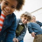 Tre børn iført efterårstøj med strik og denimjakker og tørklæde